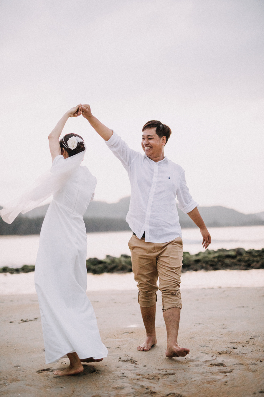 Man in White Crew Neck T-shirt and Brown Pants Holding Woman in White Dress