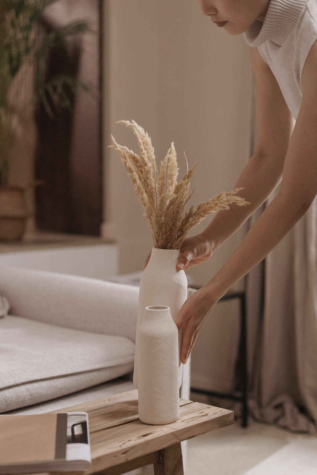 A Woman Arranging a Vase with Grass Flowers